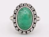 a close up of a ring with a green stone surrounded by diamonds