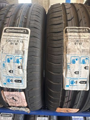 des pneus posés sur une étagère dans un magasin, sur lesquels sont collés des autocollants