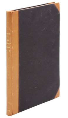 an old book with a black cover sitting on top of a white surface