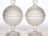 pair of cut glass urns on pedestals on a white background