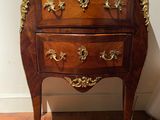 a small wooden chest of drawers on display in a room