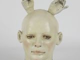 a ceramic sculpture of a woman ' s head with two hands on her head
