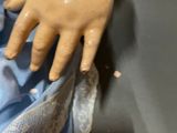 a close up of a doll ' s hand with a button on it
