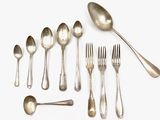 un grand nombre de cuillères et de fourchettes disposées sur la table