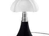 la lampe repose sur un socle noir et est dotée d'un abat-jour blanc
