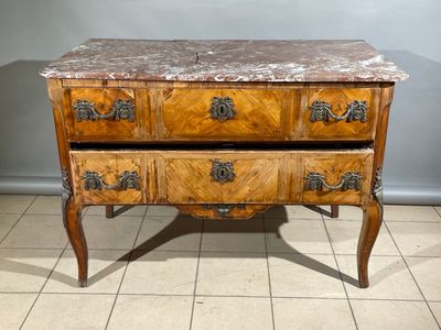 une commode au plateau en marbre posée sur un sol carrelé
