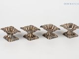 four antique silver candlesticks on a white background