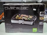 une boîte contenant un barbecue, posée sur une table dans un magasin