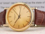 a gold watch with a brown leather strap on a table