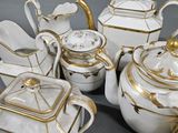 a lot of white and gold teapots and plates on a table