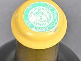 a close up of a bottle of wine with a yellow cap