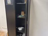 a black metal cabinet with a door open on a hard wood floor
