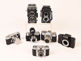 several old cameras are arranged in a row on a white surface