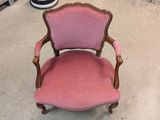 pink upholstered chair in a store with a pair of shoes on the floor
