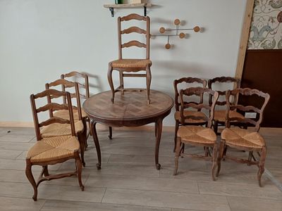 plusieurs chaises et une table dans une pièce où est accrochée une horloge au mur