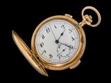 une montre de poche en or avec une chaîne, sur fond noir