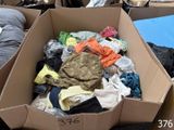 a cardboard box full of clothes on the ground