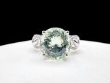 a close up of a green diamond ring on a white plate
