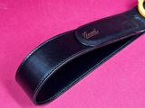 a close up of a black leather strap with a gold ring on it