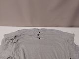 a grey shirt sitting on top of a white table next to a pair of scissors