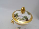 a white and gold container with a painting on it