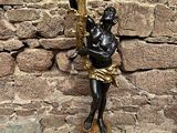 une statue représentant un homme tenant une torche devant un mur de pierre