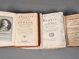 three old books are lined up in a row on a table