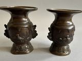 two bronze vases sitting next to each other on a table