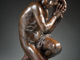 une statue en bronze représentant une femme à genoux, les mains sur le visage