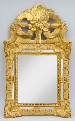 un miroir richement sculpté, avec un cadre doré, accroché à un mur blanc