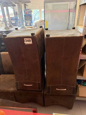 Dans un magasin, deux fauteuils en cuir marron sont empilés l'un sur l'autre.