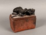 an image of a bronze statue of a dog laying on top of a box