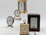 several different types of clocks on display on a white surface
