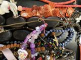 many different types of necklaces and bracelets laid out on a table