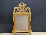 un miroir doré richement décoré, muni d'un cadre et posé sur un socle
