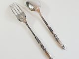 two spoons and a fork on a white table