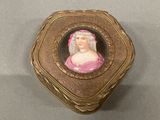 a gold box with a picture of a woman in a pink dress