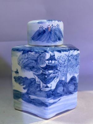 a blue and white jar with a painting on it