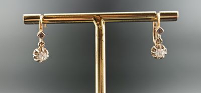 a close up of a pair of earrings on a gold stand