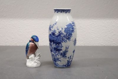 un vase bleu et blanc, avec une figurine d'oiseau à côté