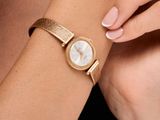 the woman is wearing a gold watch with a white dial