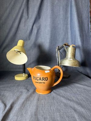 a small orange pitcher sitting next to a lamp on a table