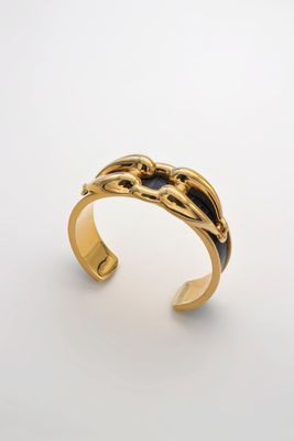une image représentant un bracelet manchette en or orné d'un motif en noir et blanc