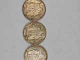 three gold coins sitting on top of each other on a white surface