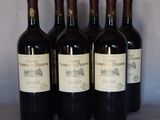 quatre bouteilles de vin rouge sont alignées sur une table