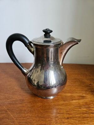 une vieille théière en argent posée sur une table en bois