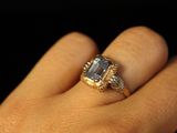 a woman ' s hand holding a ring with a blue stone on it