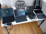 Trois ordinateurs portables sont posés sur une table sur laquelle se trouve un sac à dos.