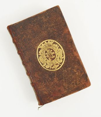 an old book with a gold emblem on it sitting on top of a white surface