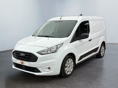 La camionnette blanche est garée dans une grande pièce au sol noir.